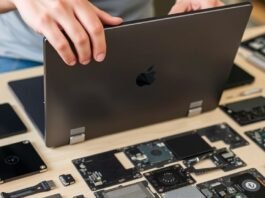 A close-up of a person unscrewing the back of a modern, modular laptop, with various components laid out on a table, highlighting the ease of repair for Right to Repair laptops.