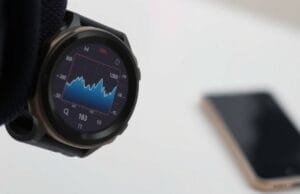 Apple wearable health and fitness: Apple Wearable Health &… A digital watch screen showing graph data, with a phone visible in the distance.