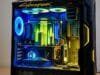Game Themed PC Build: Crafting Your Ultimate Gaming Sanctuary A highly detailed, custom-painted PC case featuring elements from Cyberpunk 2077, with neon yellow and blue RGB lighting illuminating intricate miniature cityscapes inside.