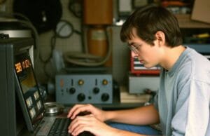 Uncover the History of Steve Jobs: His Genius Journey A young Steve Jobs focused on electronics in a garage, a scene from the early history of Steve Jobs.