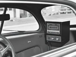 An old black and white photo of a 1940s car with a large, boxy radio telephone receiver on the dashboard, illustrating the early history of mobile phones.