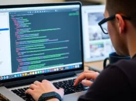Developer coding Swift on a MacBook, showing Xcode interface.